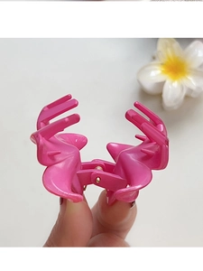 Gros plan sur la pince à cheveux rose avec ressort et détail de fleur de frangipanier