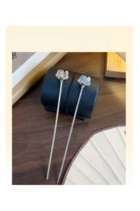 Pair of silver camellia hairpins with translucent lotus buds on a dark wooden surface