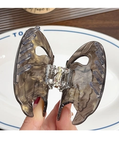 Detail of elegant butterfly hair claw clip with amber marble texture and metal spring