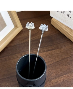 Detailed view of silver metal hairpins with elegant glass lotus buds in a desk setting