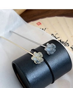 Detail of elegant camellia hair pins with translucent petals on a black stand