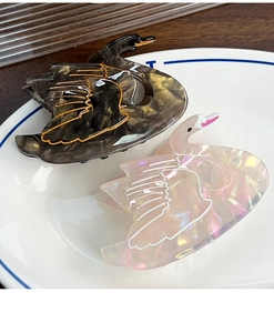 Detail of elegant swan-shaped acetate hair claws in black marble and pearlescent pink