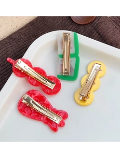 Close-up of festive hair clips featuring mahjong tiles and lucky charms on a white tray