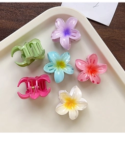Vue détaillée de six pinces à cheveux fleur de frangipanier colorées sur un plateau