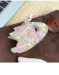 Detail of elegant swan claw clip in iridescent acetate on soft textured knit fabric