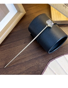 Detail of silver hair pin with iridescent flower charm on a traditional Chinese setup
