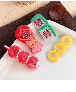 Close-up of four festive Chinese New Year hair clips with lucky bag and mahjong charms