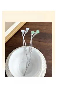 Detail of vintage lotus hairpins with white and green buds on a textured silver stem