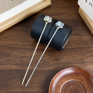 Elegant pair of silver lotus flower hairpins with crystal beads on wooden background