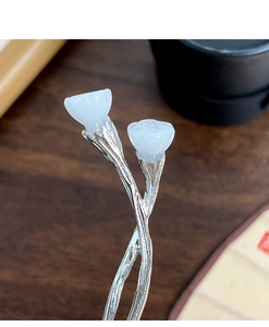 Macro detail of Chinese lotus bud hair stick with polished white stones and silver metal