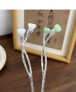 Detail of silver twisted metal hair sticks with white and green jade-like lotus buds