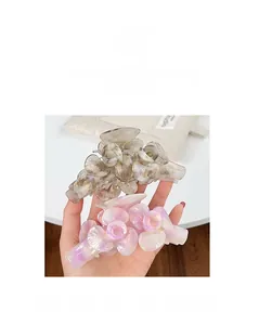 Gros plan détaillé des pinces à cheveux fleurs en acétate rose irisant et gris