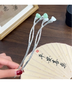 Detailed view of silver branch hairpins with green and white lotus bud accents