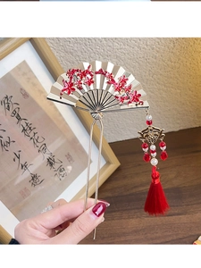 Detail of a golden fan-shaped hairpin with red plum blossoms and a long silk tassel