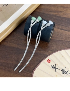 Detailed view of silver lotus hair pins with lotus buds on a dark wooden desk