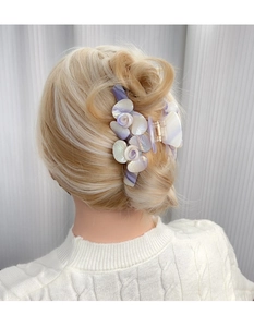 Détail d'une grande pince à cheveux fleur en acétate sur un chignon à la française