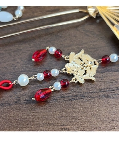 Close-up of golden floral hair fork with red faceted beads and white faux pearls