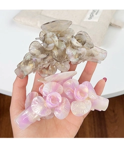 Détail de deux pinces à cheveux en acétate en forme de fleur, coloris gris et lavande