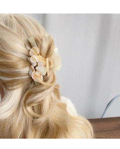 Pince à cheveux fleur en acétate crème élégante sur cheveux blonds ondulés style demi-queue