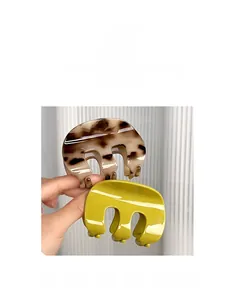 Detail view of glossy M-shaped pumpkin hair claws in tortoiseshell and avocado green