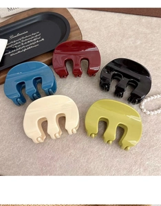 Detail view of five assorted matte hair claws in red, blue, black, beige, and olive green