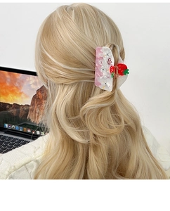 Detail view of strawberry cream hair claw clip worn on long wavy blonde hair