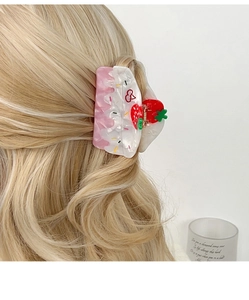 Detail view of strawberry cream hair claw clip styled on blonde wavy hair