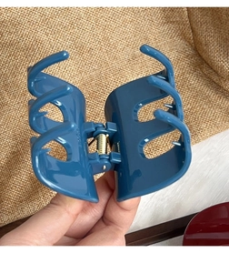Detailed view of glossy dark blue hair claw clip with golden spring on linen background
