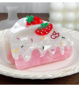Macro detail of strawberry cake hair claw clip made of pink acetate on a white plate