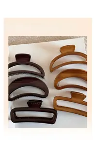 Close-up of four wood-textured hair claw clips in geometric and curved designs