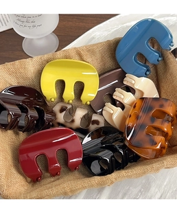 Close-up of assorted colorful resin hair claws arranged in a rustic linen basket