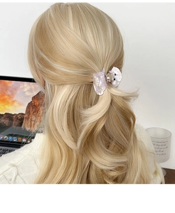 Détail de la pince à cheveux papillon marbrée lavande sur des cheveux blonds bouclés