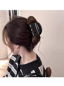 Elegant side view of a glossy black M-shaped hair claw clip styling a low bun hairstyle