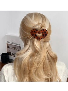 Détail d'une pince à cheveux en forme de cœur avec motif léopard sur cheveux blonds