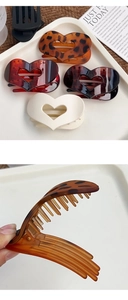 Détail de pinces à cheveux en forme de cœur évidé en léopard, écaille, noir et beige