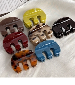 Detailed view of M-shaped pumpkin hair claws in seven assorted glossy resin colors