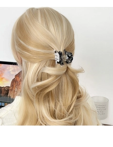 Gros plan d'une pince à cheveux motif marbre noir et blanc sur cheveux blonds