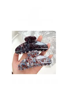 Detailed macro view of two large marble textured hair claw clips with glossy resin finish