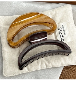 Detail of two large wood-textured claw clips in amber and dark brown for hair styling