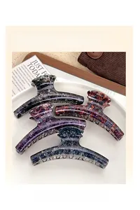 Detail showing four retro marble texture semicircle hair claw clips in varied colors on a plate