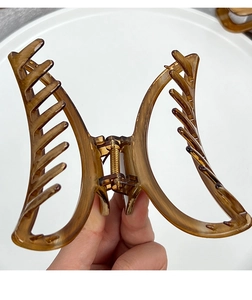 Macro view of a large amber butterfly claw clip featuring a strong gold metal spring