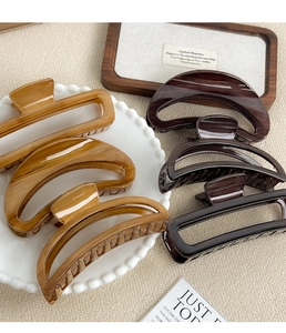 Detailed group view of wood grain texture hair claws and hollow shark clips on a tray