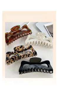 Macro shot of large hair claw clips in tortoise, pearl, and leopard patterns with gold text