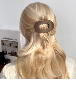 Pince à cheveux ovale marron mat présentée sur une coiffure élégante demi-haute