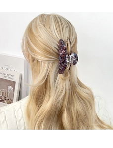 Close-up of large marble texture shark clip holding blonde hair in a sophisticated style
