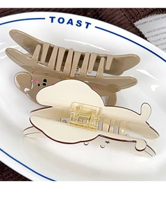 Detailed view of cute dog-themed and cream-colored hair claws in a ceramic dish