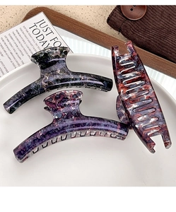 Detailed macro view of large marble hair claws in dark green, purple and tortoiseshell