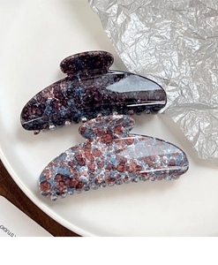 Detailed view of large marble texture shark hair clips in purple and grey blue colors