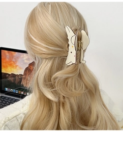 Detail of Cinnamoroll dog hair claw clip with star patterns on blonde curly hair