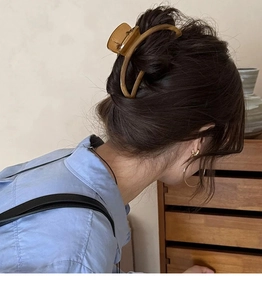 Side view of large wood grain amber hair claw clip securing a casual French bun style